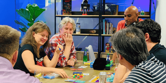 A group of people around a table playing Datopolis.