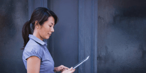 A business woman holding an iPad facing the right. 