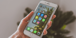 A person holding an white iphone looking at a folder of social media apps.